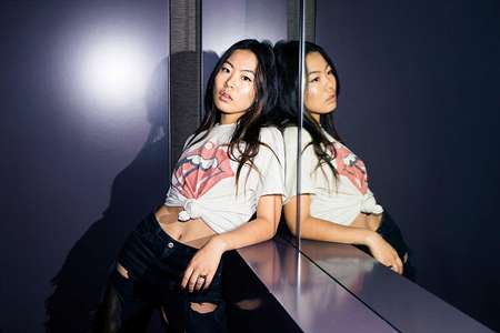 Nicole Kang leaning over a counter near the mirror to take a picture.