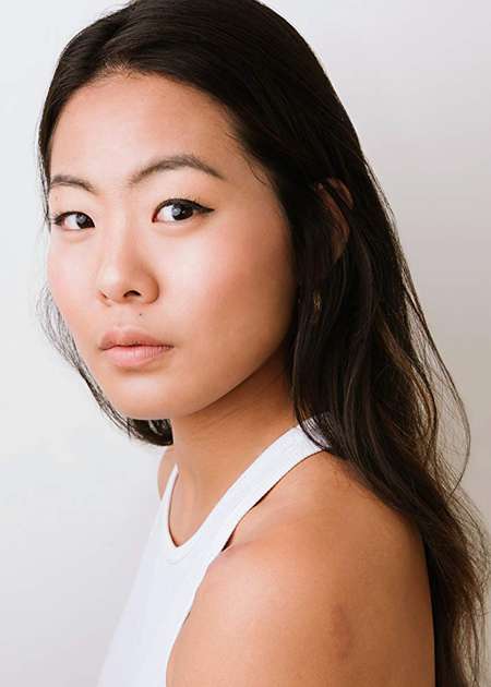 Nicole Kang is looks into the camera, wearing a white dress.