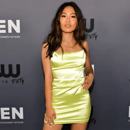 Nicole is not involved in a relationship. Posing in front of The CW banner.