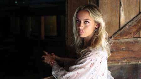 Rachel Skarsten posing for a photo wearing a white printed dress.