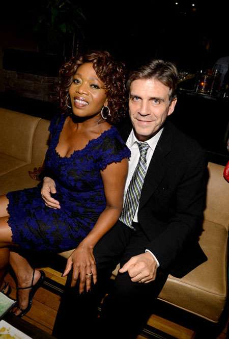 Roderick Spencer with her hand around his wife Alfre, sitting on the couch.