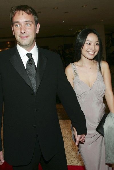 Trey (left) holding Emma's hand while wearing a suit and Emma is in a light drey revealing dress.